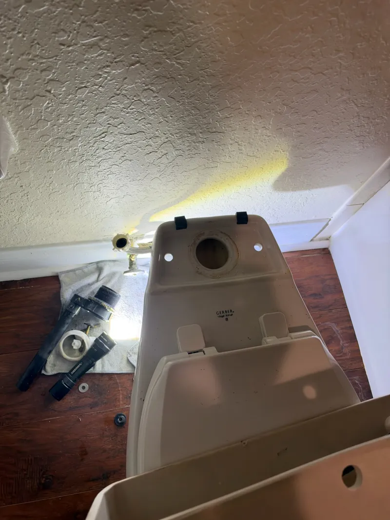 Toilet tank lifted off the bowl with the old flush parts laid out on a towel