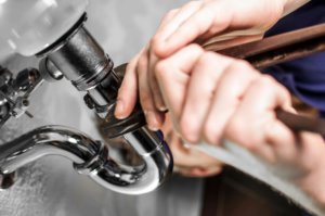 Close-up of a plumber’s hand repairing a pipe in a home plumbing system