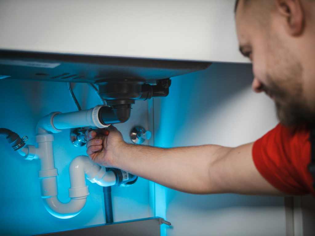 plumber repairing pipes under the kitchen sink